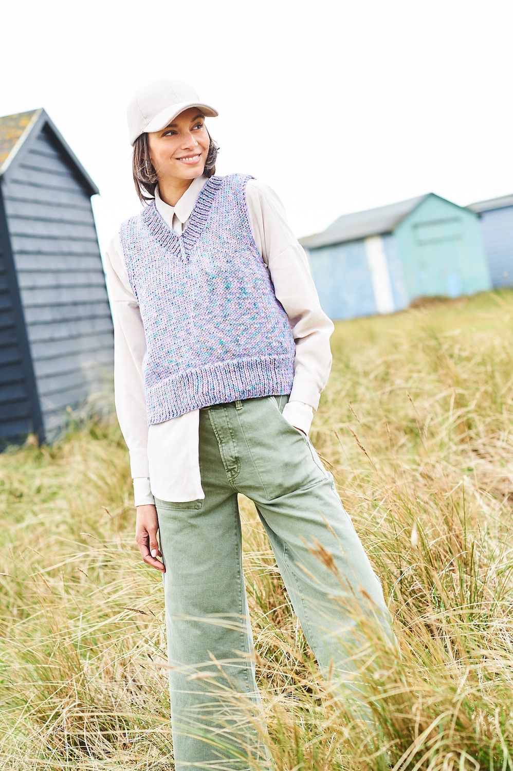 A woman is wearing a knitted tank top in a variegated purple yarn.