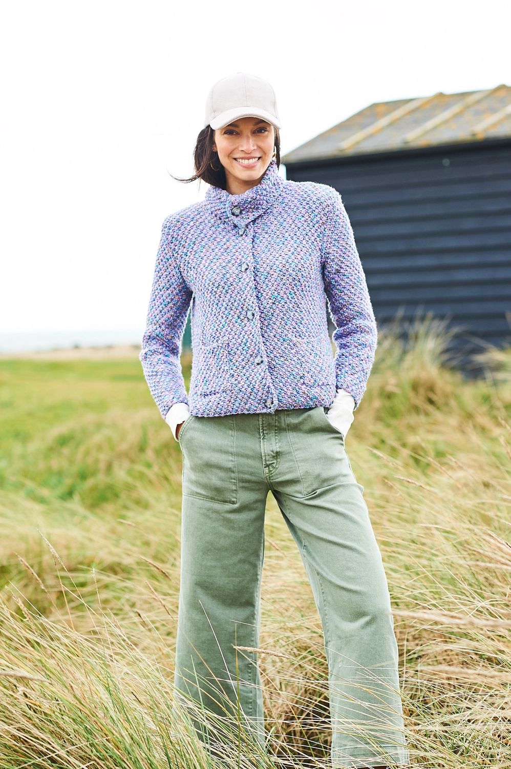 A woman is wearing a knitted jacket in a variegated pale purple yarn.