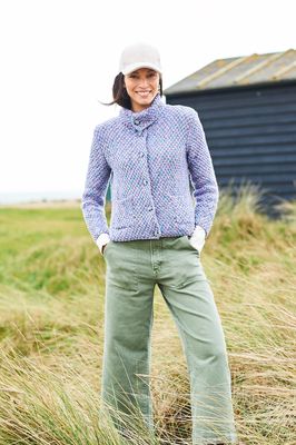 A woman is wearing a knitted jacket in a variegated pale purple yarn.