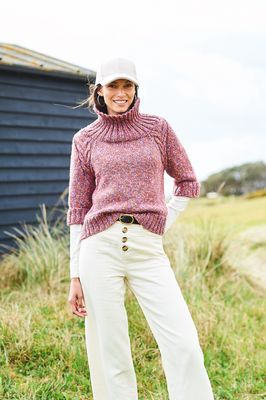 A woman is wearing a knitted sweater in a variegated pink-brown yarn.