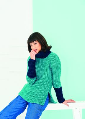 A woman is wearing a teal knitted sweater with navy blue sleeves.