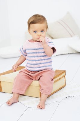 A baby is wearing a pink crocheted top with blue stripes.
