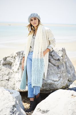 A woman is wearing a cream and duck egg knitted scarf.