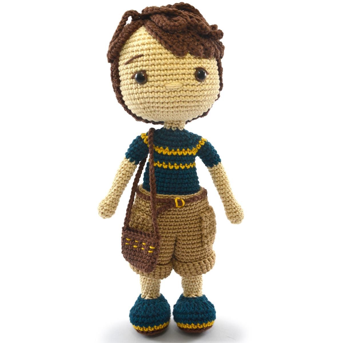A crocheted doll, of a white boy with brown hair, a blue t-shirt, brown shorts and blue shoes.