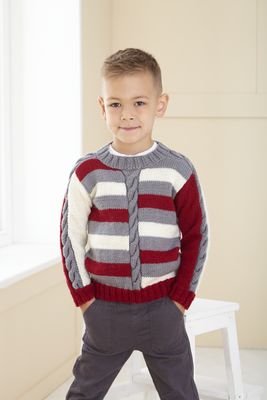 A boy is wearing a cream, red and grey stripy knitted sweater.