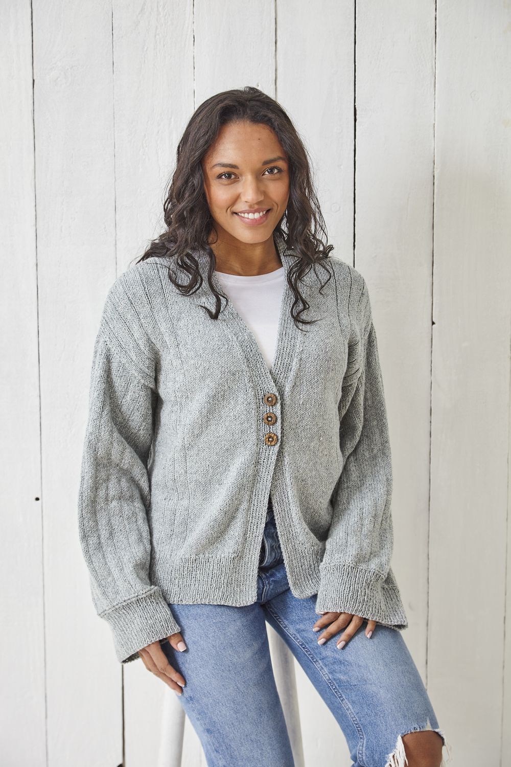 A woman is wearing a pale grey knitted cardigan.