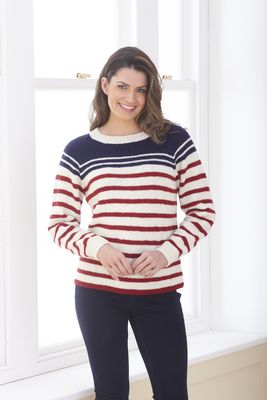 A woman is wearing a cream, red and navy blue stripy knitted sweater.