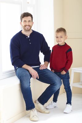 A man is wearing a navy blue knitted sweater and a boy is wearing a red knitted sweater.