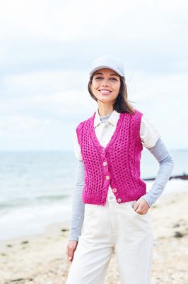 A woman is wearing a pink cable knit waistcoat.