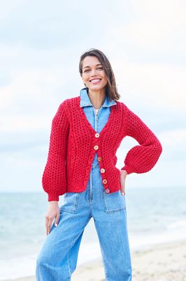 A woman is wearing a red cable knit cardigan.