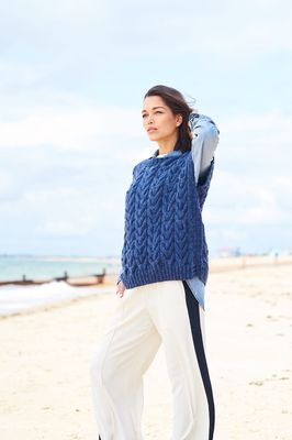A woman is wearing a dark blue cable knit tank top.