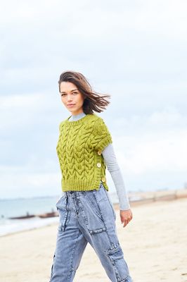 A woman is wearing a lime green cable knit tank top.