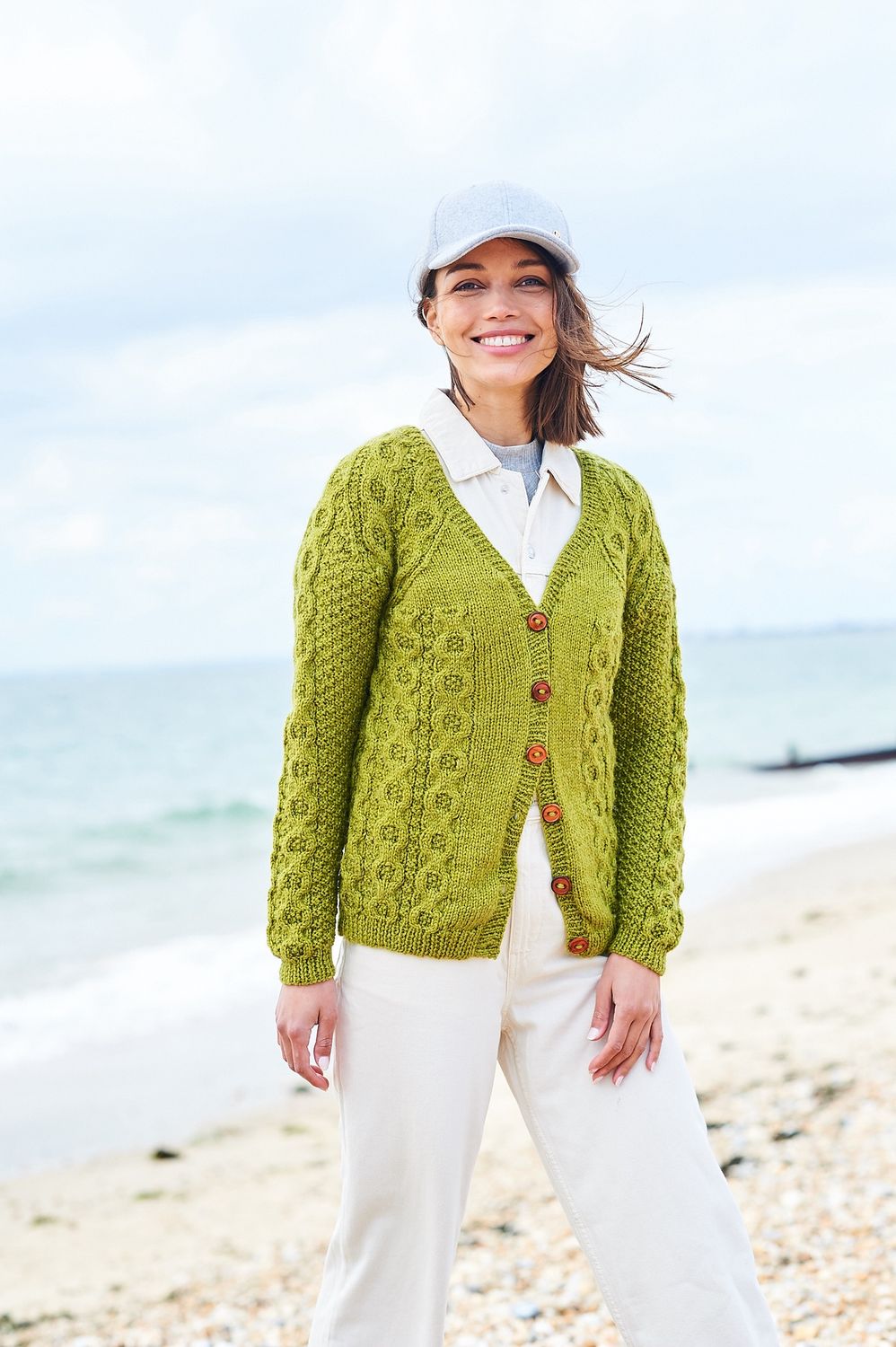 A woman is wearing a lime green cable knit cardigan.
