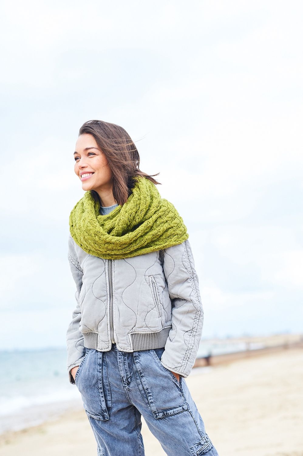 A woman is wearing a lime green cable knit cowl.