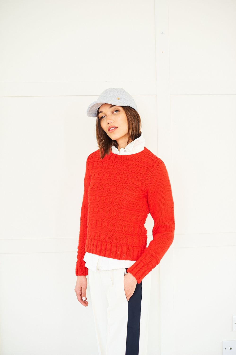 A woman is wearing a bright red knitted sweater.