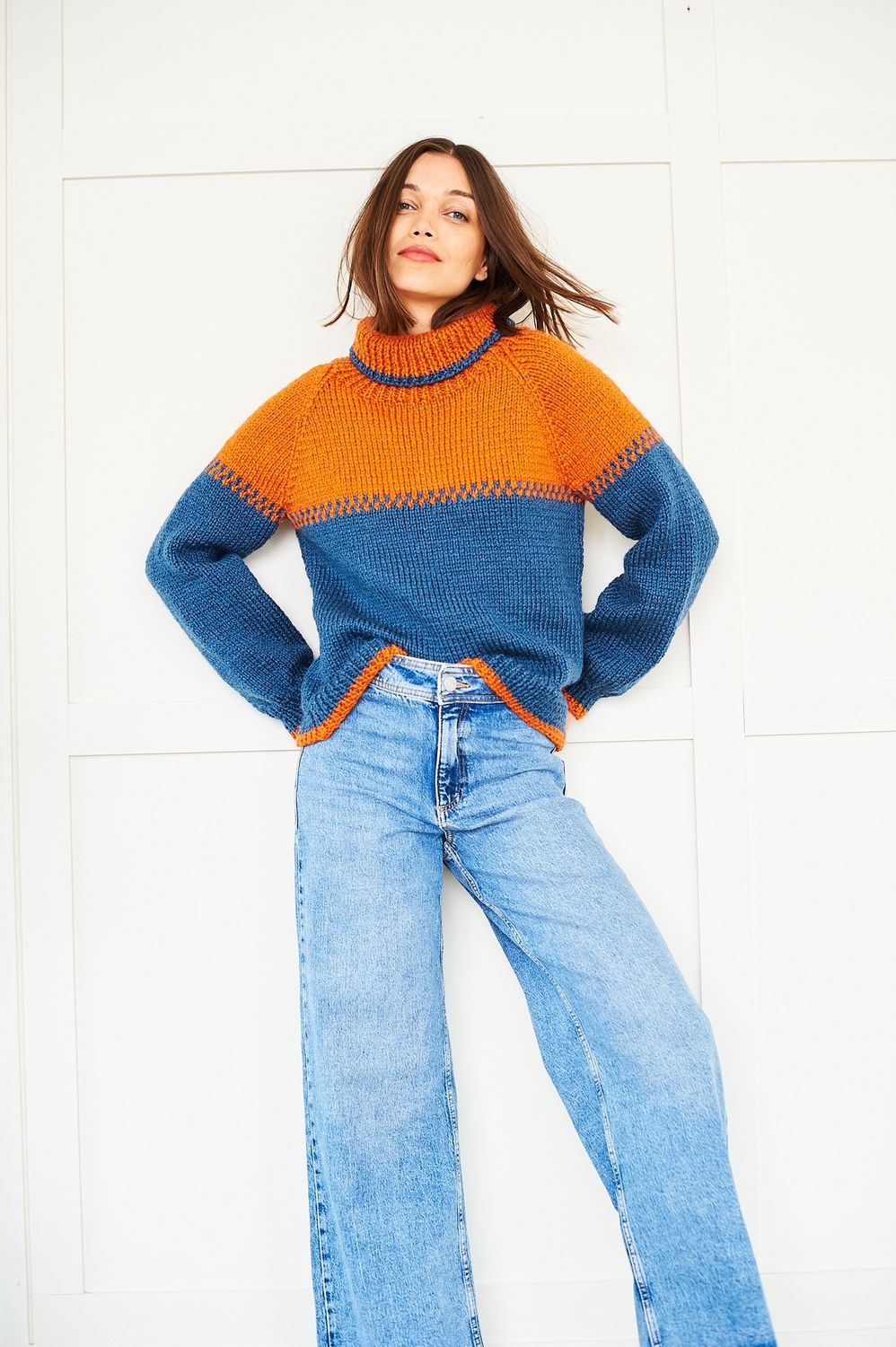 A woman is wearing an orange and dark blue knitted sweater.