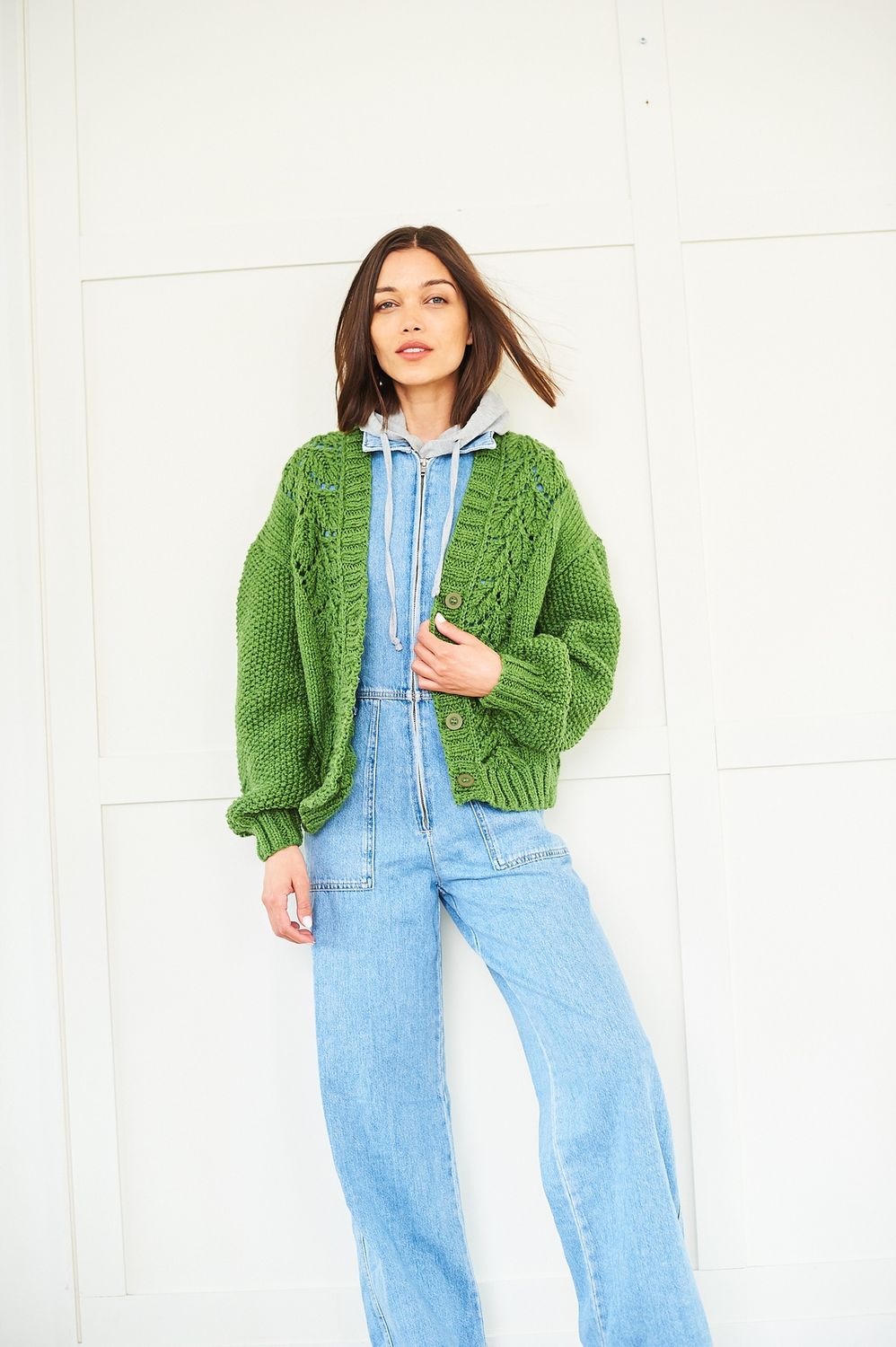 A woman is wearing a green knitted cardigan with lace down the front.