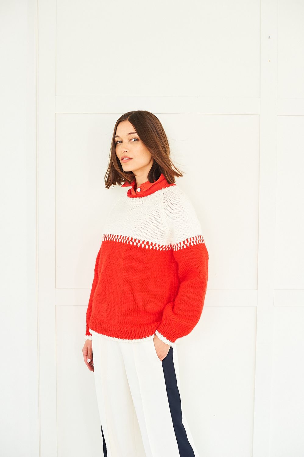 A woman is wearing a cream and red knitted sweater.