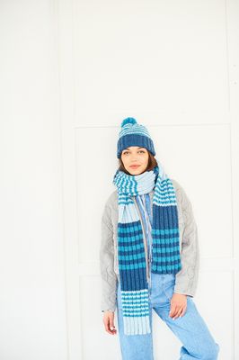 A woman is wearing a blue stripy knitted scarf and matching hat.