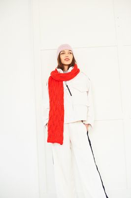 A woman is wearing a bright red lace knitted hat and light pink lace knitted hat.