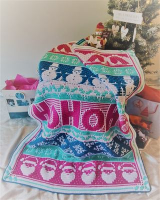 The festive design crocheted blanket in shades of white, pink, blue and teal.