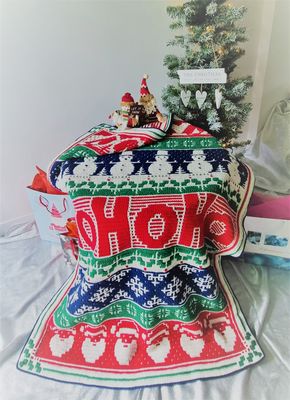 The festive design crocheted blanket in shades of cream, red, green and navy blue.