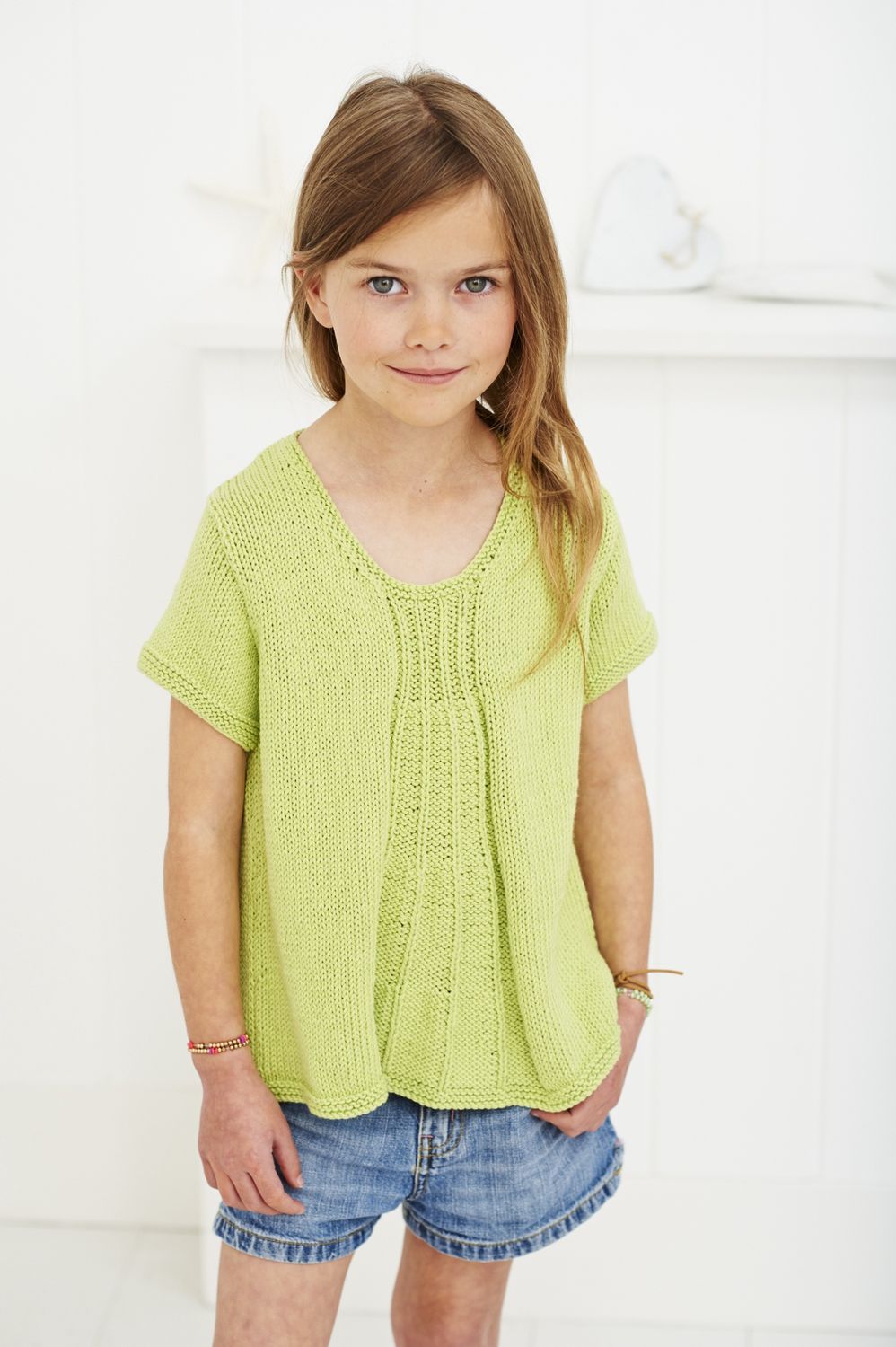 A girl is wearing a light green knitted top.