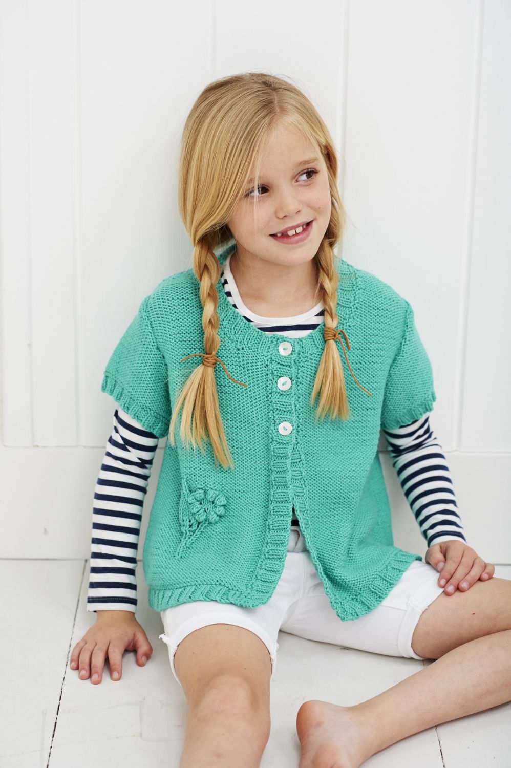 A girl is wearing an bright mint green knitted cardigan.