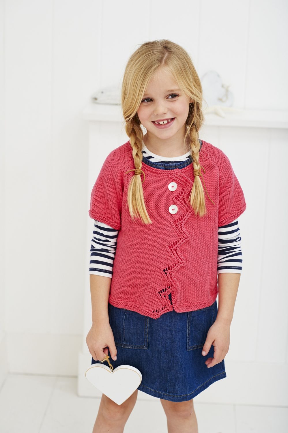 A girl is wearing a bright pink knitted cardigan.