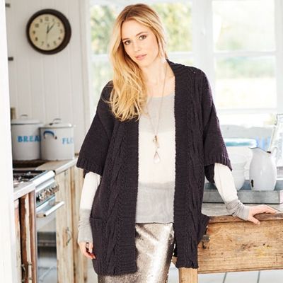 A woman is wearing a black knitted cardigan.