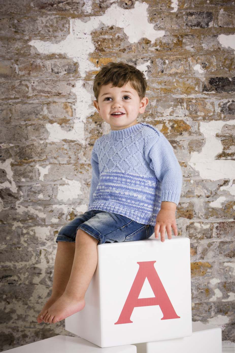 A boy is wearing a blue cable knit sweater.