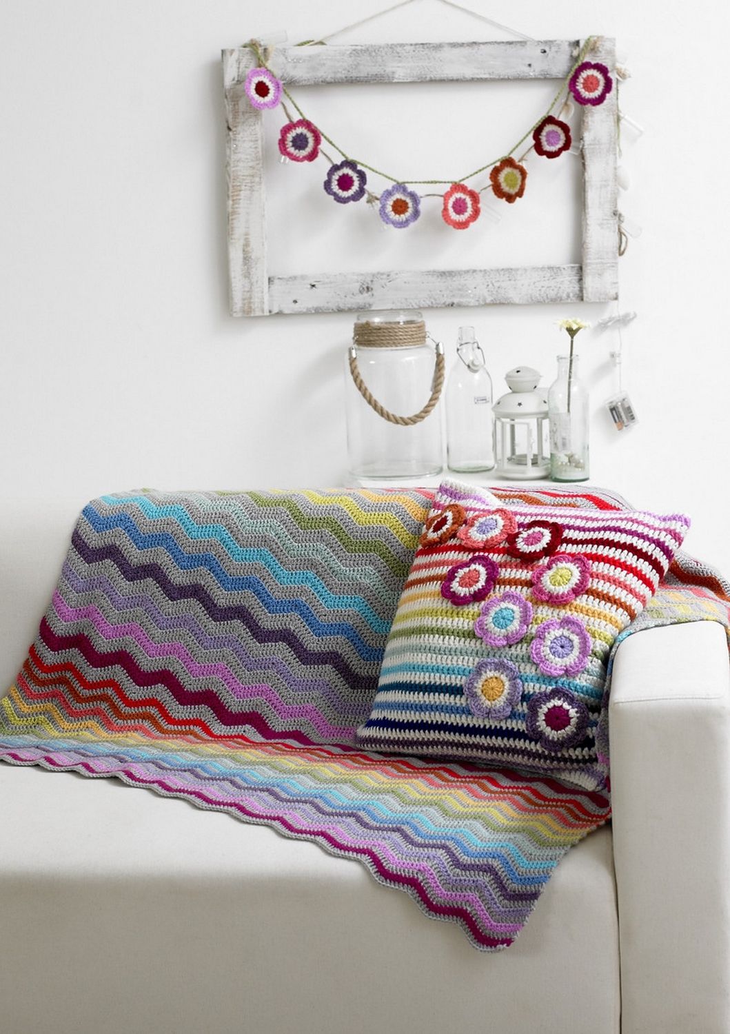 A grey and rainbow crocheted ripple blanket and matching cushion.