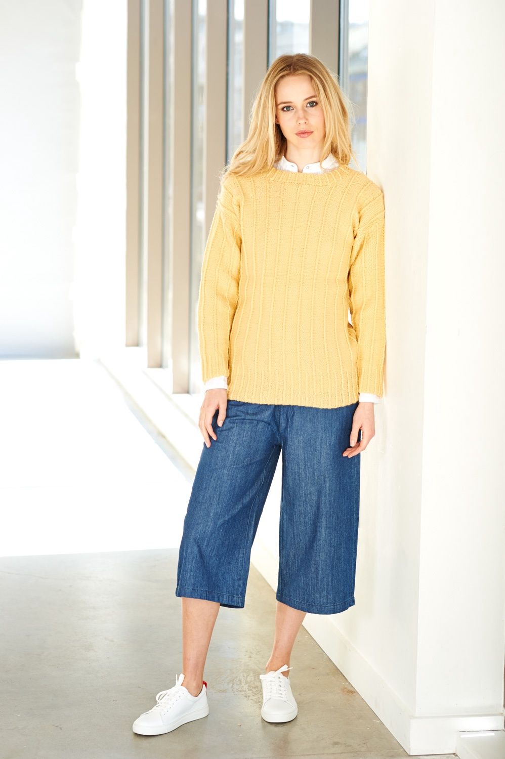 A woman is wearing a yellow knitted sweater.