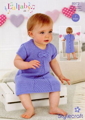 A baby is wearing a purple knitted dress.