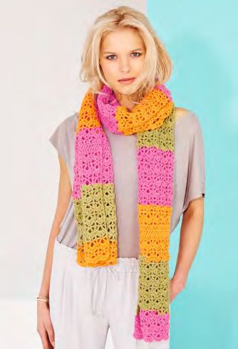 A woman is wearing a crocheted scarf in a variegated pink, orange and green yarn.