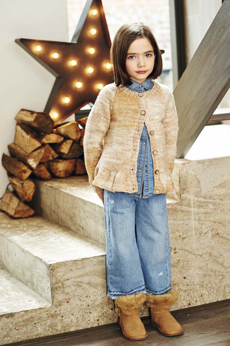 A girl is wearing a knitted cardigan in a variegated beige yarn.