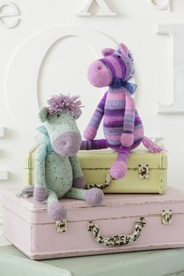 A mint green crocheted donkey and a stripy purple crocheted horse.