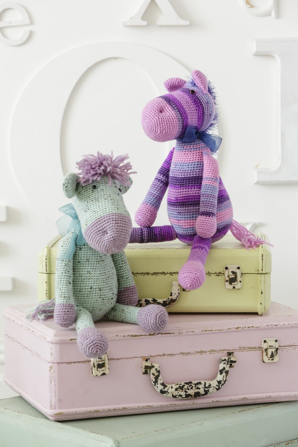 A mint green crocheted donkey and a stripy purple crocheted horse.