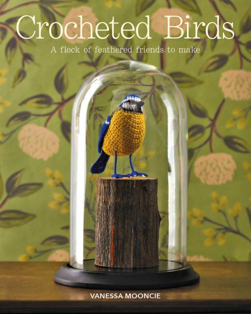 The front cover of the book, showing a crocheted bird in a glass case.