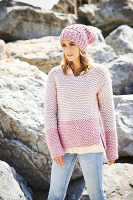 A woman is wearing a light pink knitted sweater.