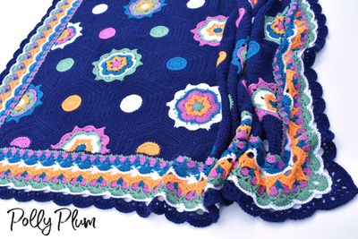 A crocheted blanket made up of hexagons in blue, green, orange and purple.