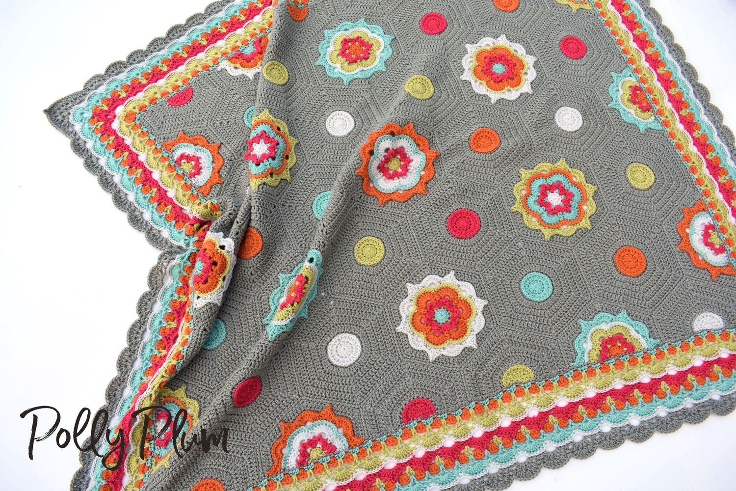 A crocheted blanket made up of hexagons in grey, blue, green, pink and orange.