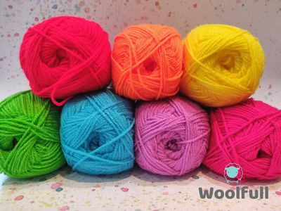 7 balls of yarn in bright rainbow shades piled up.