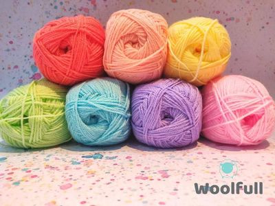 7 balls of yarn in pastel rainbow shades piled up.