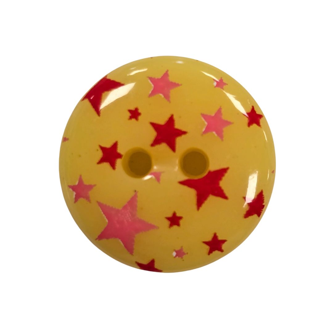 A round yellow button with pink and red stars printed on.