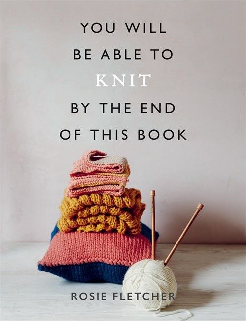 The front cover of the book, showing a pile of knitted items and a pair of knitting needles in a ball of yarn.