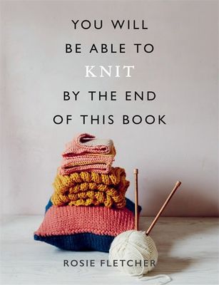 The front cover of the book, showing a pile of knitted items and a pair of knitting needles in a ball of yarn.