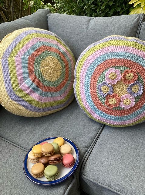 2 round, knitted cushions in yellow, pink, green, blue and purple.
