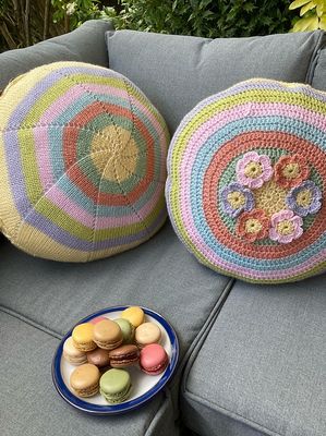 2 round, knitted cushions in yellow, pink, green, blue and purple.