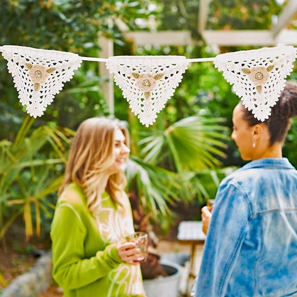 Cream crocheted bunting hanging in a garden.
